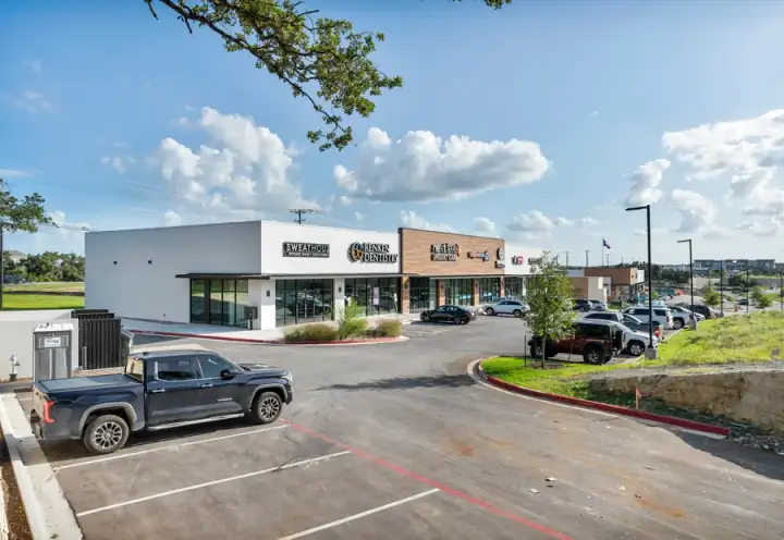 Leander-area commercial corridor with retail storefronts, parking, and Central Texas sky