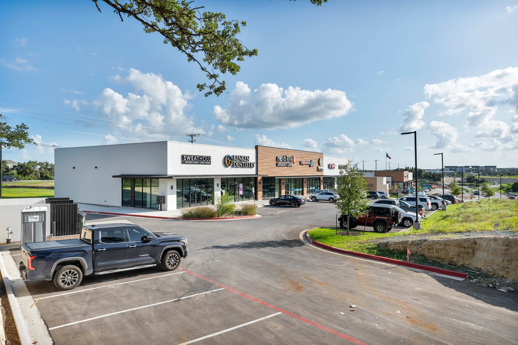 Leander-area commercial corridor with retail storefronts, parking, and Central Texas sky