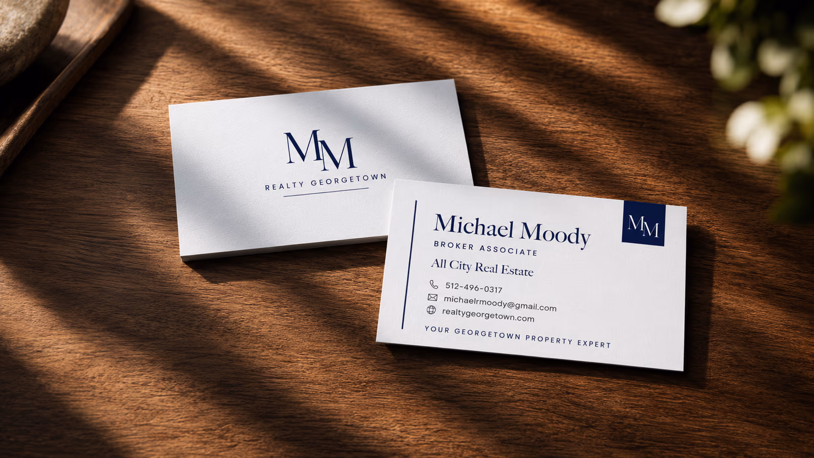 Michael Moody Realty Georgetown business cards on a sunlit wood table